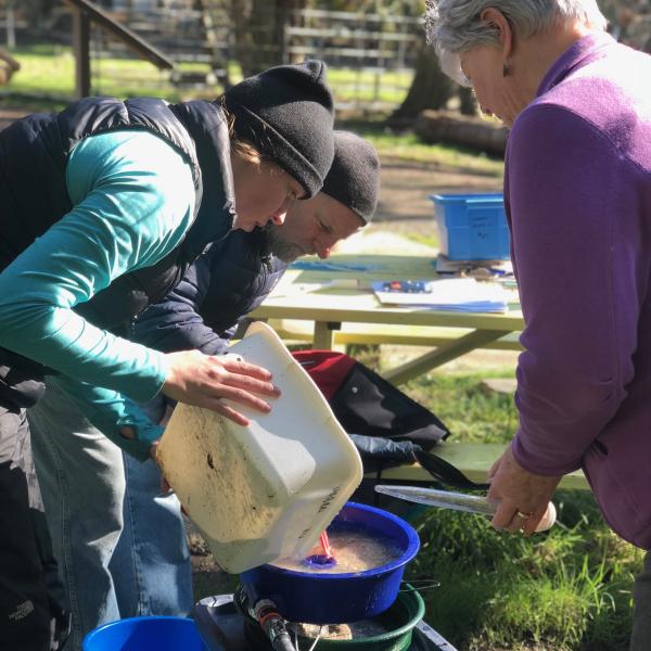 Three people processing sediment samples through vortex and filter