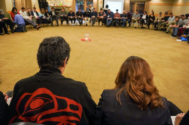 Participants at the IHII Launch sitting in a circle with their heads bowed down